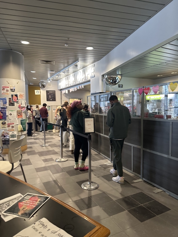 Picture of a cafe with people waiting in line.