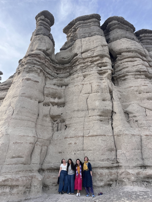 Four of the Dartmouth women in front of a big white rock formation at Plaza Blanca. Light blue sky at the top of the photo. 