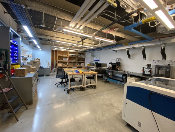 A student workshop with 3D printers and laser cutters situated within an industrially built room. 
