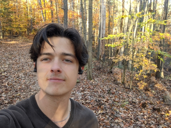 Me in the forest at Dartmouth surrounded by yellow leaves on the trees and the ground