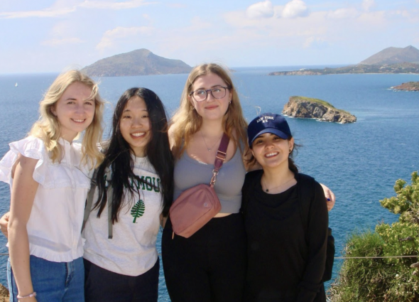 four women stand with an ocean backdrop