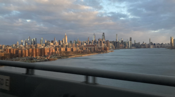 A view of New York City. The sky is cloudy, on the image's left is Manhattan, on the image's right is the Hudson River.