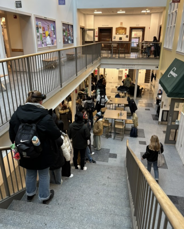 A view of the Phở Bar line. Students stand in line along the basement and staircase of the Collis Center.