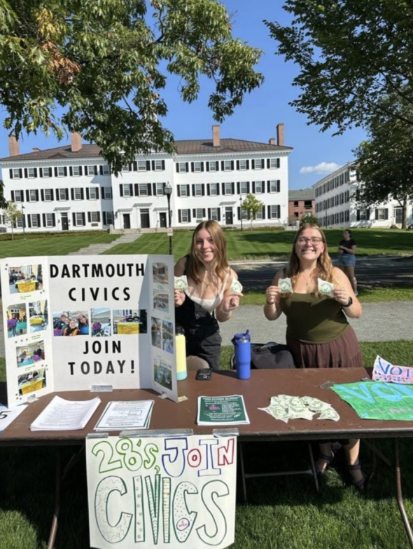 Lia and I standing behind the Civics table at the Student Involvement fair, holding Dartmouth Civics stickers. Dartmouth Hall is in the background.