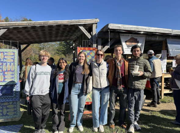 6 Dartmouth Civics members smiling in front of a stand at the Norwich Farmers Market