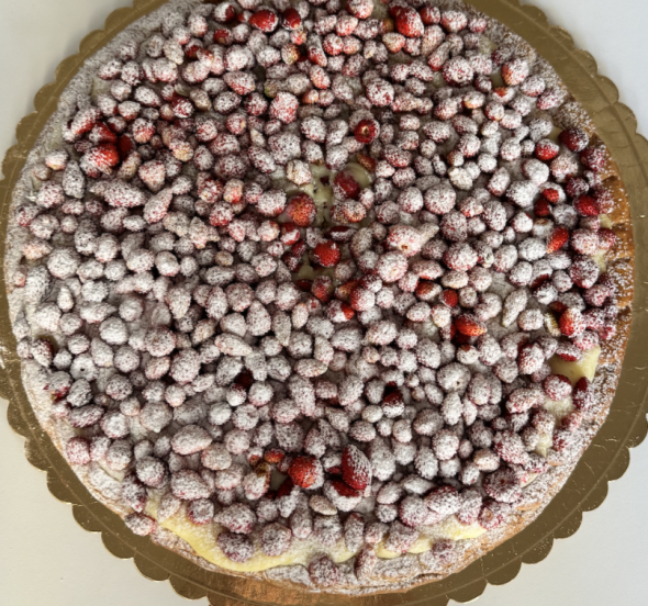A tart covered in mini strawberries with powdered sugar on top