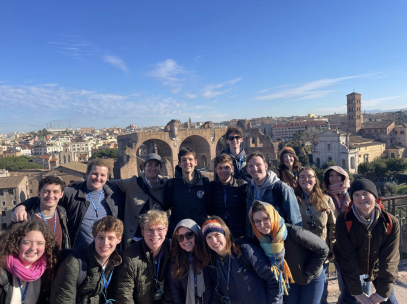 The LSA+ standing and smiling on a view overlooking the Roman Forum. They are wearing winter jackets and tour group radio sets.