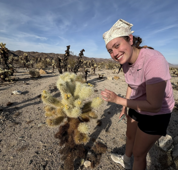 A woman in pink tee stands next to a fuzzy but spiky cactus.