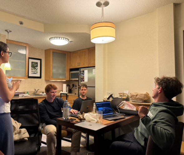 A messy room filled with food, computers, and a lot of chit chat.