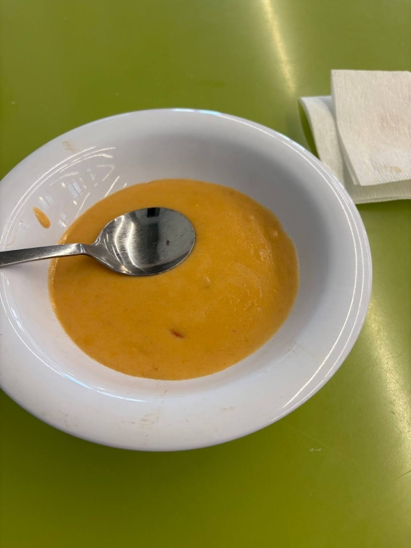 A white bowl filled with a creamy-looking soup and a spoon. There's also a napkin on the side.