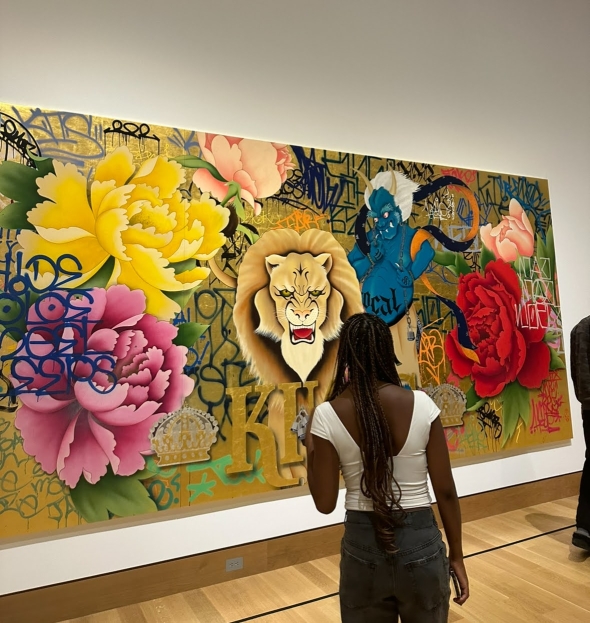 A girl is facing her back towards the camera as she looks at a colorful mural in the museum. 