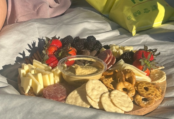 Close-up of a charcuterie board with various cheeses, meats, fruits, and crackers, created by friends for a lunch picnic on the Green at Dartmouth.