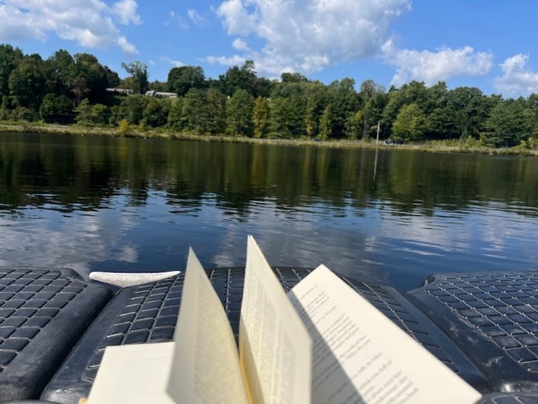 An image of an open book on a swimming dock next to a river