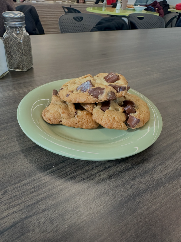 Three chocolate chip cookies on a green plate.