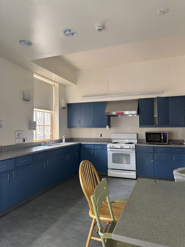 A dorm kitchen, with lots of counter space, an oven, a sink, a microwave, and a table.