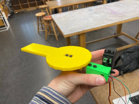 a yellow and green 3D-printed component attached to a servo-motor.