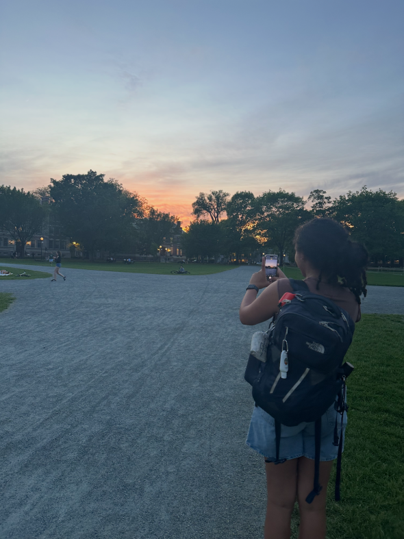 Picture of a girl taking a picture of a sunset.