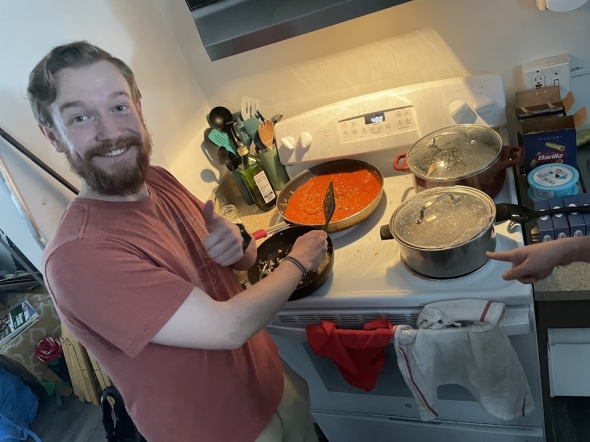 a boy smiling over a sauce pan while cooking