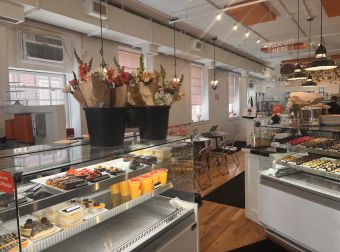 Desserts on display and seating area with white and pink details.