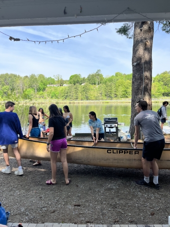 A photo of a few students getting out a Clipper, a large canoe, near the clubhouse