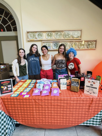 a group of 5 standing behind a table with colorful parcels