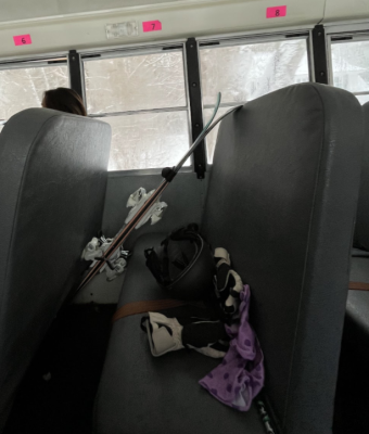 A side-view picture of the bus. Skis and other equipment lay on the bench. You can see snow out the window