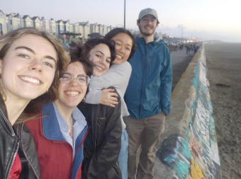 a selfie picture of smiling teens by the beach at sunset.